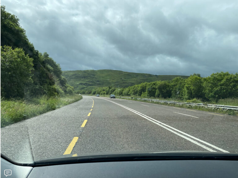 A picture showing driving in Ireland with a road and mountains.